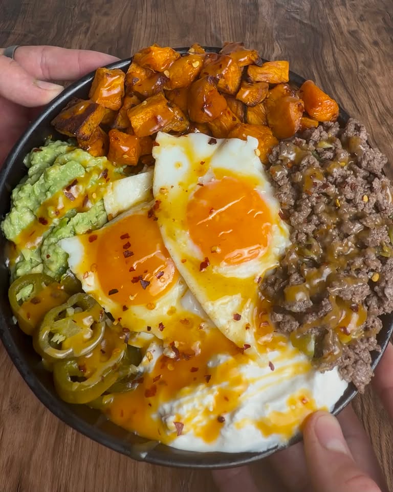 Loaded bowl with fried eggs, beef, roasted sweet potato, guac and jalapeños